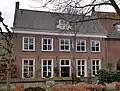 Eenvoudig huis met gevel in schoon werk, dwars rood zadeldak in het verlengde van dat van nummer 1