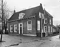 Dwarshuis met pannen zadeldak tussen puntgevels en rechts een opkamer. Deur met eenvoudige omlijsting en hoofdgestel. Achter het huis een uitspringende vleugel onder pannen schilddak. Tot 1912 had het de functie van pastorie van de Hervormde Gemeente.