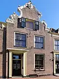 Pand met topgevel in de vorm van een ingezwenkte halsgevel gevat in weelderig zandstenen rococo-ornament (vormt een geheel met de nrs. 39 en 43)