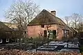 Boerderij van het Kempische langgeveltype, met rieten wolfdak met voet van pannen, met vrijstaande deels bakstenen, deels houten schuur onder rieten wolfdak. Een tweede schuur onder rieten wolfdak achter de boerderij