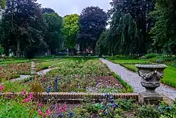 Gezicht op de tuin met een tuinvaas op een van de keermuren rond het terras
