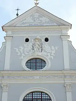 Timpaan met jaardicht. Ovale vensters in de voorgevel.