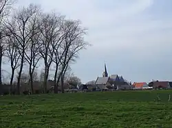 Zicht op Koolkerke, met centraal de Sint-Niklaaskerk en op de achtergronde de windmolens in het Brugse binnenhavengebied.