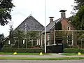 Kop-hals-rompboerderij met topgevels met zesruitsvensters, lijsten met boeiborden en topschoorstenen met borden