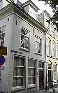 Pand met gepleisterde lijstgevel met mansardedak. Hoekpand Ambachtstraat