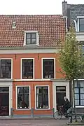 Rechter gedeelte van een pand met verdieping en door pannen gedekt zadeldak, evenwijdig aan de straat. Deuromlijsting midden 19e eeuw, cordonlijst en houten kroonlijst. Stoep met hardstenen paaltjes