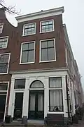 Pand met bakstenen gevel met rechte kroonlijst. Onderpui met houten pilasterstelling, zijgevel zijde Herengracht met deur en deuromlijsting. Onderpui 19e eeuw. Gerestaureerd 1940