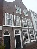 Pand met brede tuitgevel. In 19e eeuw onderpui gewijzigd