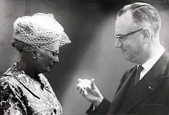 Voor zijn verdiensten bij de Kamer van Koophandel in Rotterdam krijgt Lichtenauer een erepenning die hij aan zijn vrouw toont. 5 september 1961.