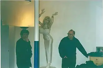 De regisseur Jan Bucquoy (rechts met bril) plaatst een pop van Lolo Ferrari aan de ingang van een cinema voor de première van Camping Cosmos in (1996) voor een perplexe toeschouwer.