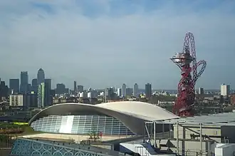 Aquatics Centre na de verbouwingen van 2013 waarbij de tribunes werden verkleind en glazen wanden werden ingevoegd. Naast het Centre de ArcelorMittal Orbit.