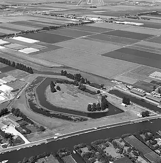 Fort bij Aalsmeer vanuit de lucht gezien; 1977. Ervoor de Ringvaart en erachter de Geniedijk en het Voorkanaal met de sluizen.