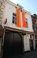Huis met eenvoudige lijstgevel. Koetspoort in een omlijsting van blokwerk.