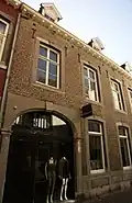 Huis met lijstgevel en een rondbogige koetspoort in Naamse steen.