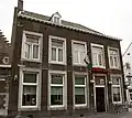 Hoekhuis, waarvan de eenvoudige lijstgevels voorzien zijn van vensters in Naamse steen.