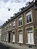 Huis met brede lijstgevel, voorzien van hardstenen omramingen met gecanneleerde steentjes onder de zijkanten.