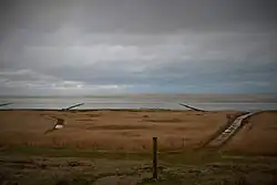 Vest for Mandø By. I forgrunden Stormflodssøjlen. I baggrunden anes Koresand.