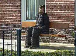 Stenen mannetje op bankje (Jan Schoffelmeijer, 2010). Zie ook vrouwelijke tegenhanger bij Euvelgunne.