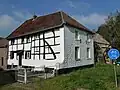 Hoeve met binnenplaats, grotendeels van vakwerk op een breukstenen onderbouw. Geschoord dakoverstek