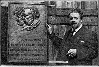 Marinus Vreugde naast plaquette van wijlen David en Greta Lobo - Braakensiek, 1927