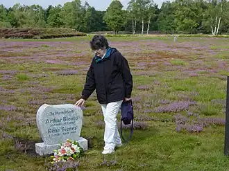 Holocaust-overlevende Marion Bienes bij het plaatsen van een grafsteen voor haar omgekomen broer en vader in het voormalige concentratiekamp Bergen-Belsen