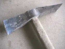 Een niet-parallelle steenhouwersbijl, met steenhouwersmerk in de steel