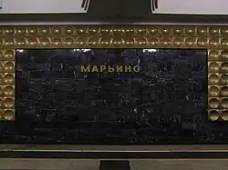 De stationsnaam tussen de aluminiumtegels op de tunnelwand.