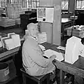 Medewerker met boeken in losse katernen, 1965