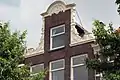 Pand met halsgevel met gebeeldhouwde vleugelstukken en fronton en met jongere onderpui