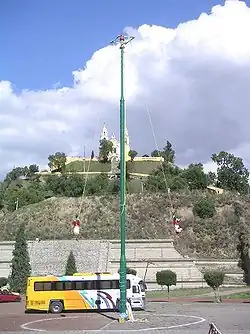 Het ritueel voladores (vliegende dansers) met de piramide op de achtergrond