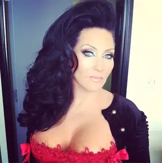 Een foto van een vrouw in een rode jurk die direct in de camera kijkt