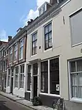 Huis met gepleisterde rechte gevel in lijst gedateerd 1784. Voordeuromlijsting met consoles en rozetbovenlicht. Stoep