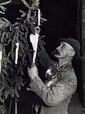 Een mijnwerker met carbidlamp versiert de kerstboom in een zoutmijn met zoutkristallen, 1933