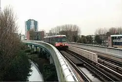 Een metro nadert het station, het gemeentehuis op de achtergrond.