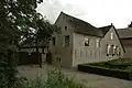 Boerderij met rechte puntgevel en links onderkelderd gedeelte onder zadeldak met puntgevel, parallel aan de straat lopend. Peilstenen, herinnerend aan hoge waterstanden in 1740 en 1800