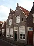 Huis met gekoppelde puntgeveltjes, oorspronkelijk wellicht trapgevels, en boven de gewijzigde pui twee gevelstenen met anno en 1651