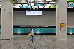 Tunnelwand met de aluminium panelen en de stationsnaam.