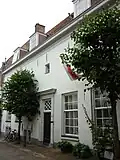 Huis met gepleisterde lijstgevel. In wezen 17e-eeuws huis. Voordeur met houten pilasters