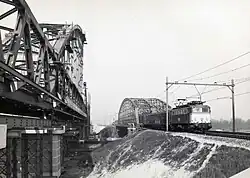 Locomotief serie 1100 over de oude spoorbrug. Links de nieuwe brug in aanbouw.