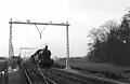 NS 6106 met een goederentrein op een spoorlijn tijdens electrificatiewerkzaamheden. (1952)