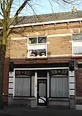 Woonhuis (oorspronkelijk woonhuis-winkel). Decoratieve winkelpui.