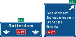 K4: Hoge beslissingswegwijzer langs autosnelweg met rijstrookpaneel voor de doorgaande richting en aftakkingspaneel voor de afgaande richting, met interlokale doelen, routenummers autosnelwegen en Europese hoofdroutes
