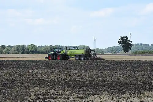Figuur VI: tandem mestoplegger uitgevoerd met een zwanenhals en rugzuigarm met achterop een bouwlandbemester met schijven