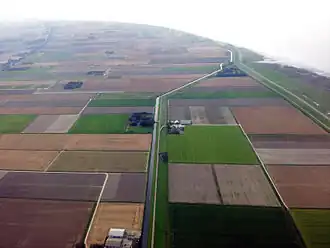 Nieuwe Bildtdijk richting het westen langs de Nieuwe Bildtdijkstervaart, aan het einde Zwarte Haan en rechts de Waddenzee