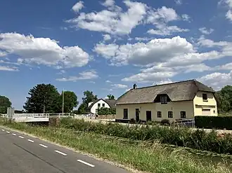 Nieuwe Brug, gezien vanaf de Zeedijk. Het gele gebouw is de voormalige schuur van het tolhuis, het witte gebouw is de voormalige herberg.