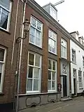 Woonhuis en opslagruimte. Gevel uitgevoerd in baksteen. Deur met houten pilasters en rijk versierd bovenlicht