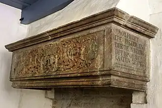 Zandstenen schouw die volgens een opschrift dateert uit 1540 (MDXL). Oorspronkelijk mogelijk uit de borg Bolhuis. Later herplaatst in de in 1888 afgebroken boerderij Zwarte lap/De Palen bij Westerwijtwerd. In 1930 in bezit gekomen van het Groninger Museum. In 1974 op de huidige plek geplaatst. De schouw met Renaissance-kenmerken verbeeldt de zondeval en de vlucht uit het paradijs. Links en rechts staan mogelijk de wapenschilden van de families Van Bolhuis en Van Halsema