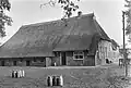 "Holsener", boerderij onder rieten schilddak, onderschoer; rechts een uitbouw van het woongedeelte. Vensters met roedenverdeling, met luiken behangen; houten schuurtje onder een met riet en pannen gedekt schilddak en met ingang in de lange zijde