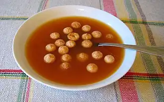 Een bord rozenbottelsoep met kleine beschuitjes gemaakt van amandelen