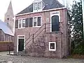 Voormalig raadhuis. Gebouwtje met schilddak. De verdieping bereikbaar via een buitentrap naar een bordes
